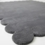 Close up angle showing the dense wool texture and plush cut pile of the Aether Dior dark grey rug edge.