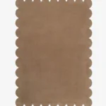 Top down view of the Amber Glint tan colored hand tufted wool rug on a white background showing the rectangular shape and scalloped edges.