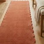 Close-up angled view of the Autumn Embrace runner rug on a wooden floor, highlighting the dense, plush hand-tufted New Zealand wool and viscose silk texture and the gracefully contoured warm terracotta scalloped border.