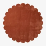 Top down flat lay of the Burnt Clay round wool rug showing the rich rust color and scalloped border.