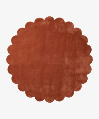 Top down flat lay of the Burnt Clay round wool rug showing the rich rust color and scalloped border.