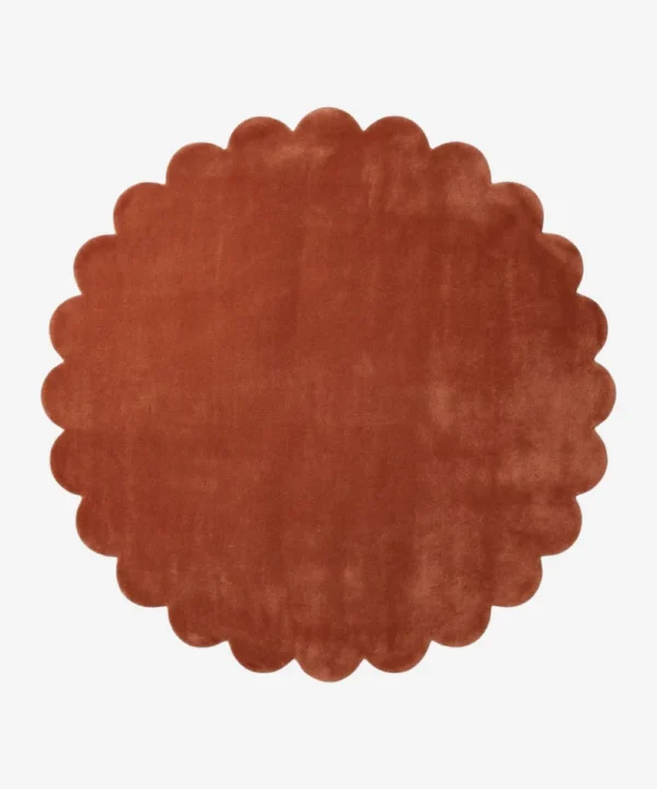 Top down flat lay of the Burnt Clay round wool rug showing the rich rust color and scalloped border.