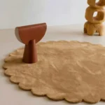 Close up angled perspective of the Camel Dawn round rug showing the plush golden tan wool texture and cut pile.