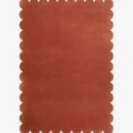 Top down view of the Clay Ember reddish brown hand tufted wool rug on a white background showing the rectangular shape and scalloped edges.