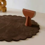 Close up angled perspective of the Cocoa Crest round rug showing the plush dark brown wool texture and cut pile.