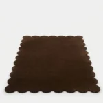 Front perspective view of the Cocoa Earth hand tufted wool rug isolated on a white background displaying the full scalloped design.