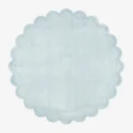 Top down flat lay view of the Ice Whisper round rug showing the soft light blue wool color and scalloped border.