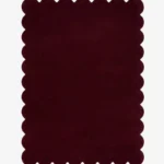 Top down view of the Merlot Plum dark purple hand tufted wool rug on a white background showing the rectangular shape and scalloped edges.