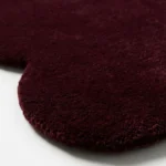 Close up angle showing the plush wool texture and high quality cut pile of the Merlot Plum rug edge.