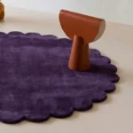Close up angled shot of the Plum Eclipse rug highlighting the plush dark purple wool pile and craftsmanship.