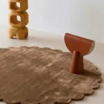 Close up angled perspective of the Sandstone round rug showing the plush taupe wool texture and cut pile.