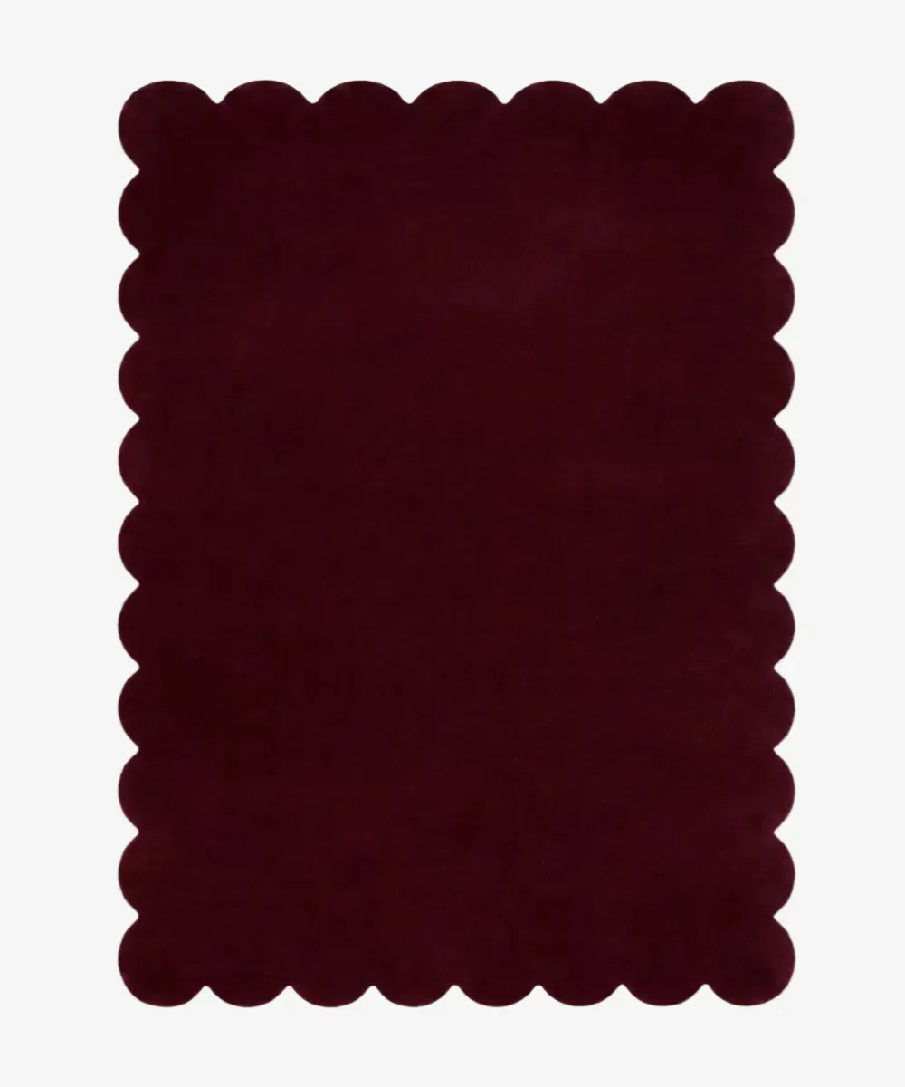 A solid maroon wool rug with wavy borders, serving as the button to explore the Rectangular Rugs collection.