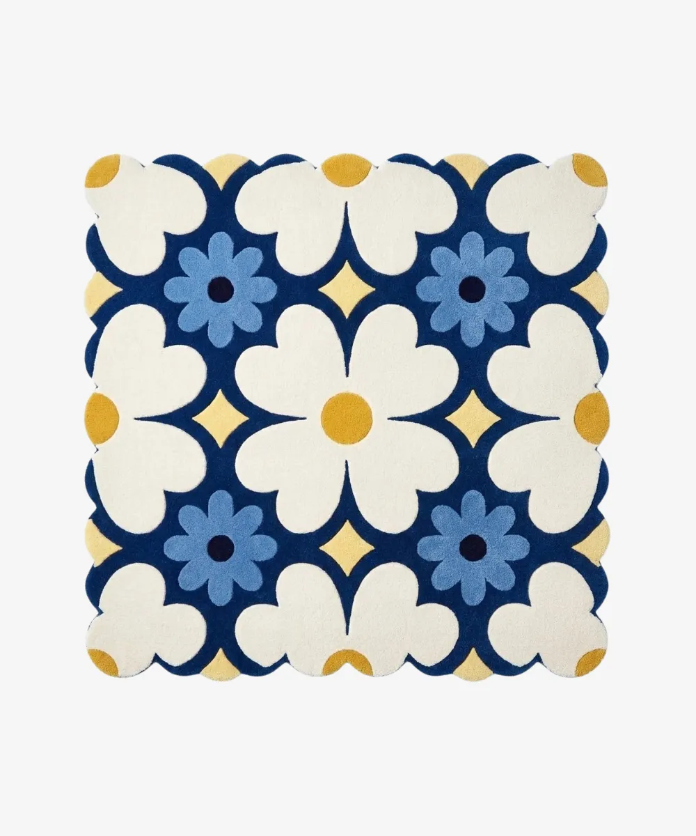 A square rug featuring a blue and white floral pattern with scalloped edges, linking to the Square Rugs category.