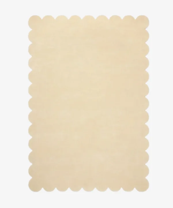 Top down view of the Vanilla Crest cream colored hand tufted wool rug on a white background showing the rectangular shape and scalloped edges.