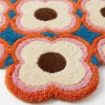 Extreme close up detail of the Blush Bloom rug highlighting the dense plush wool pile and the vibrant colors of the hand carved floral motifs.