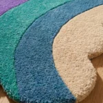 Extreme close up showing the dense hand tufted wool texture of the Chromatic Wave rug, highlighting the vibrant teal and blue stripes against the cream pile.