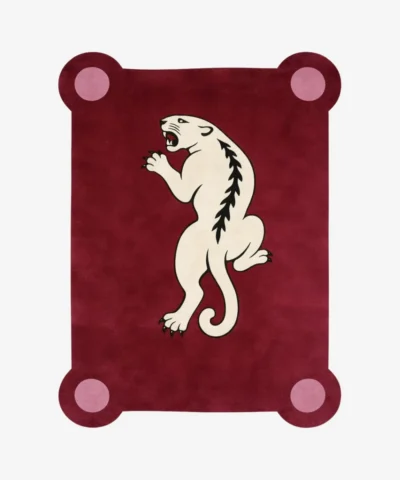 Top down view of the Crimson Prowl rug featuring a deep maroon wool background with a stylized white panther climbing design and pink circular corner accents.