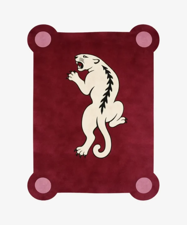 Top down view of the Crimson Prowl rug featuring a deep maroon wool background with a stylized white panther climbing design and pink circular corner accents.