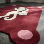 Close-up low angle view of the Crimson Prowl rug, highlighting the plush hand-tufted wool texture, the embossed white panther design, and the distinct rounded corner with a solid pink accent circle.