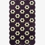 Top down view of the Daisy Night rug featuring a grid of small white daisy flowers on a deep purple wool background with scalloped borders.