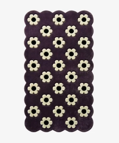 Top down view of the Daisy Night rug featuring a grid of small white daisy flowers on a deep purple wool background with scalloped borders.