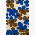 Top down view of the Earthen Dusk rug featuring a retro floral pattern with bold blue and brown flowers on a color blocked cream background with scalloped edges.