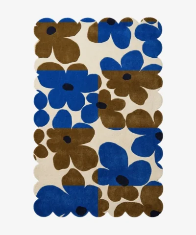 Top down view of the Earthen Dusk rug featuring a retro floral pattern with bold blue and brown flowers on a color blocked cream background with scalloped edges.