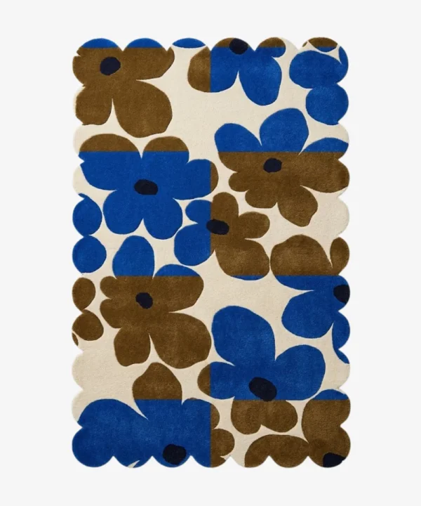 Top down view of the Earthen Dusk rug featuring a retro floral pattern with bold blue and brown flowers on a color blocked cream background with scalloped edges.