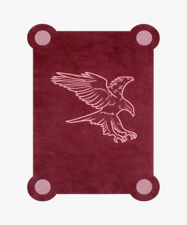 Top down view of the Ember Crest rug featuring a deep maroon wool background with a stylized light pink line art illustration of an eagle in flight, framed by decorative circular corner accents.