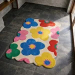 Perspective view of the Flora Fiesta rug placed on a dark tiled floor, featuring a playful retro pattern of large, colorful flowers in vibrant blue, yellow, pink, red, and green with intricate starburst centers on a cream background, finished with a petal-contoured scalloped edge.