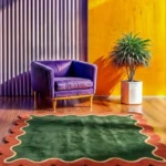 High angle view of the Forest Frame rug on a wooden floor, highlighting the square shape and the precise hand-tufted contrast between the green center and scalloped border.