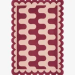 Top down view of the Garnet Loop rug featuring a rich maroon wool background with a bold cream wavy geometric pattern and custom scalloped edges.