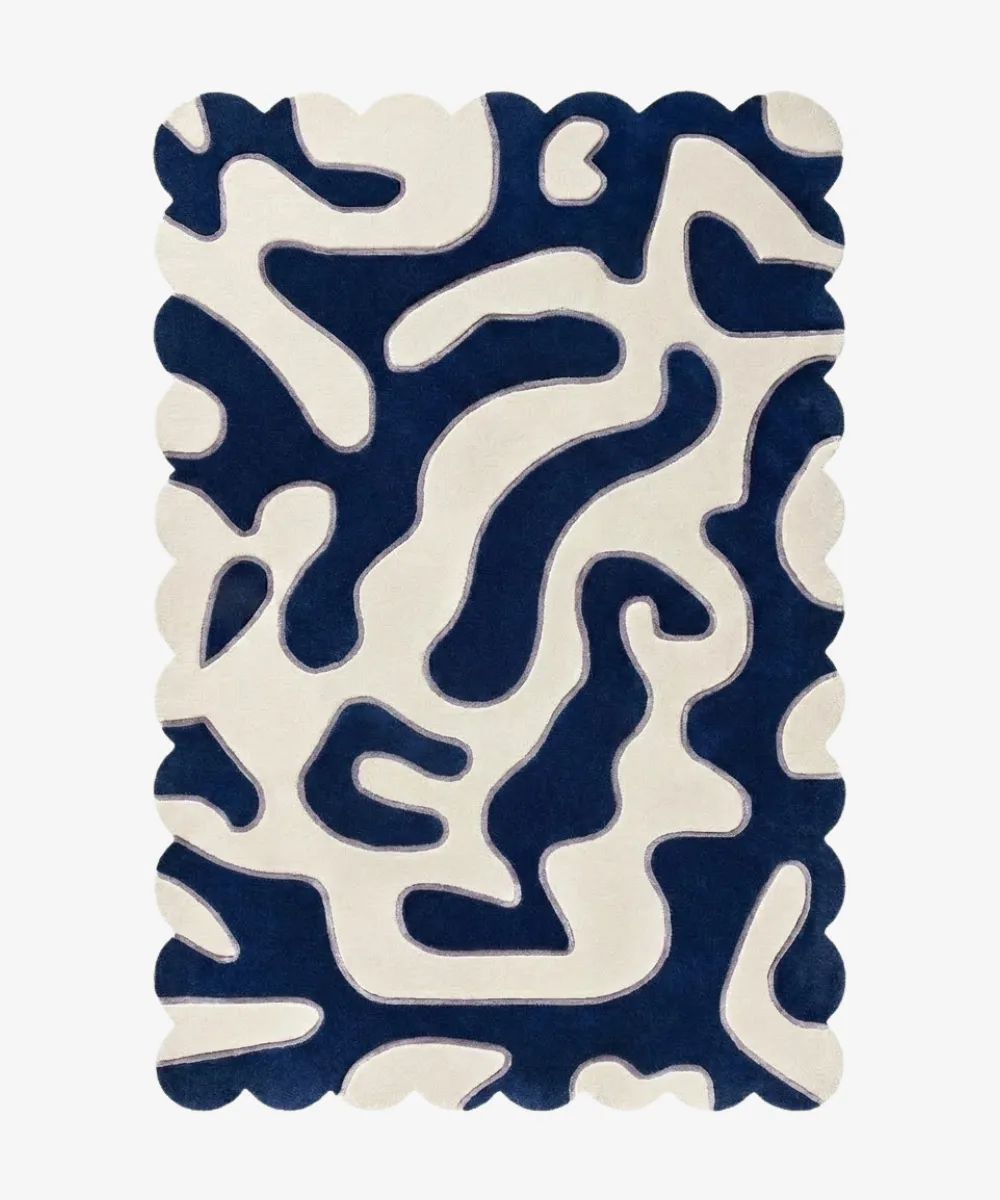 Top-down view of the Inked Dyed rug against a white background, featuring a bold, organic, maze-like abstract pattern in solid deep blue and cream, framed by a continuous scalloped border.