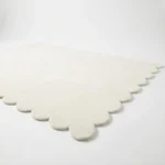 Low angle perspective shot of the Ivory Drift area rug highlighting the dense plush pile height and the elegant curved shape in a neutral tone.