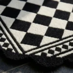 Close-up folded detail of the Ivory Lattice rug, showcasing the plush, dense hand-tufted wool texture, the embossed dark brown geometric lattice pattern, and the intricately carved dark brown scalloped border.