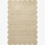 Top down view of the Milky Ridges rug featuring a solid cream color with horizontal carved textures and decorative scalloped edges.