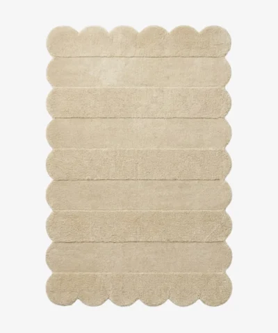 Top down view of the Milky Ridges rug featuring a solid cream color with horizontal carved textures and decorative scalloped edges.