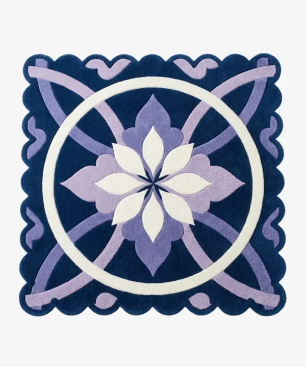 Top down view of the Moon Blossom rug featuring a central geometric flower motif in white and lavender on a deep navy blue background with scalloped edges.