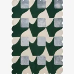 Top-down view of the Moss Rhythm square rug against a white background, featuring a repeating geometric patchwork pattern of squares and rectangles in varying shades of earthy green and subtle grey, framed by a continuous solid green scalloped border.