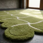 Close-up low angle view of the Moss Weave rug, highlighting the plush hand-tufted wool texture, the embossed cream wavy grid lines, and the intricate moss green scalloped border.