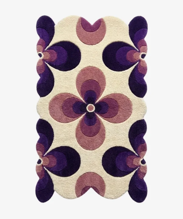 Top down flat lay of the Nocturne Bloom rug featuring a retro geometric floral pattern with dark purple and lilac petals on a cream wool background.