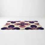 Low angle perspective shot of the Nocturne Bloom area rug showing the soft plush texture and the unique wavy border of the purple and beige design.