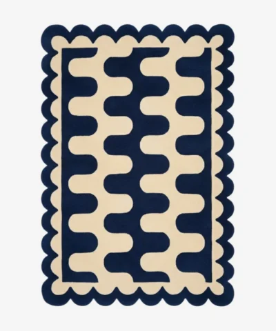 Top down view of the Obsidian Grid rug featuring a deep navy blue wool background with a bold cream wavy geometric pattern and custom scalloped edges.