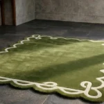 Perspective view of the Olive Reverie rug on a tiled floor, highlighting the soft hand-tufted wool texture and the contrasting cream loop design against the deep green pile.