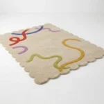 Low angle side profile of the Pastel Doodle area rug highlighting the dense plush wool pile and the clean finish of the hand cut scalloped edges.