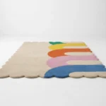 Low angle side profile of the Rainbow Arcana area rug highlighting the dense plush wool pile height and the vibrant modern arc design on the edge.