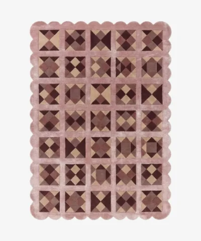 Top down view of the Rose Matrix rug against a white background, featuring a repeating patchwork pattern of geometric squares and diamonds in solid shades of soft pink, mauve, and deep burgundy, framed by a continuous pink scalloped border.