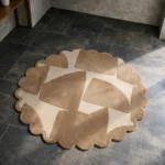 High angle view of the Rounded Dunes round rug featuring a modern abstract geometric design in warm sand and cream tones, finished with a decorative scalloped edge.
