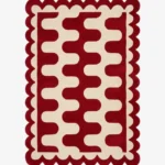 Top down view of the Ruby Weave rug featuring a deep red wool background with a bold cream wavy geometric pattern and custom scalloped edges.