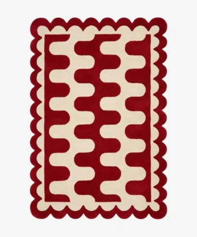Top down view of the Ruby Weave rug featuring a deep red wool background with a bold cream wavy geometric pattern and custom scalloped edges.